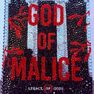 May include: A book cover with the title "GOD OF MALICE" in large red letters. The cover is black with a pattern of black and white vertical stripes and is embellished with sparkling crystals. The author's name, Rina Kent, is at the bottom.