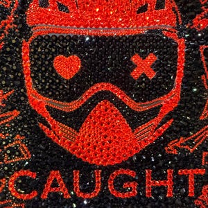 May include: A book cover with a black background covered in sparkling embellishments. The title "CAUGHT UP" is in red, along with the author's name "NAVESSA ALLEN". A red graphic of a helmet and mask is in the center. The text "AN INTO DARKNESS NOVEL" is at the bottom.