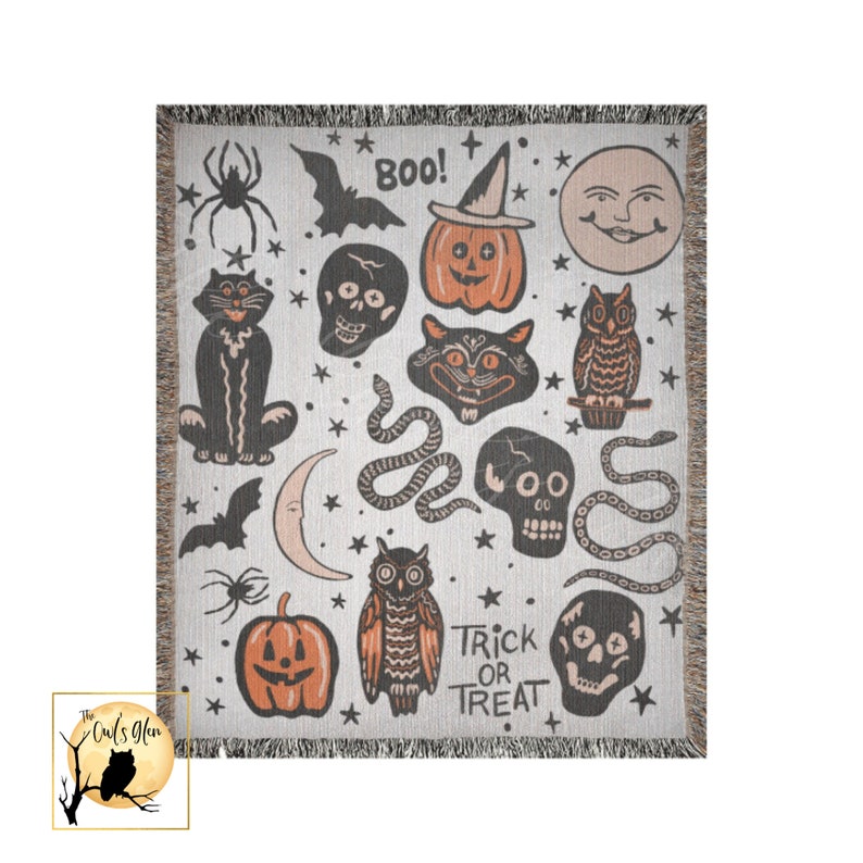 Puede incluir: Una manta tejida con fondo blanco y un patr&oacute;n repetido de iconos de Halloween. Los iconos incluyen un gato negro, una calavera, una serpiente, una calabaza, un b&uacute;ho, un murci&eacute;lago, una luna creciente y estrellas. El texto "Boo!" y "Trick or Treat" tambi&eacute;n est&aacute; incluido en el patr&oacute;n.
