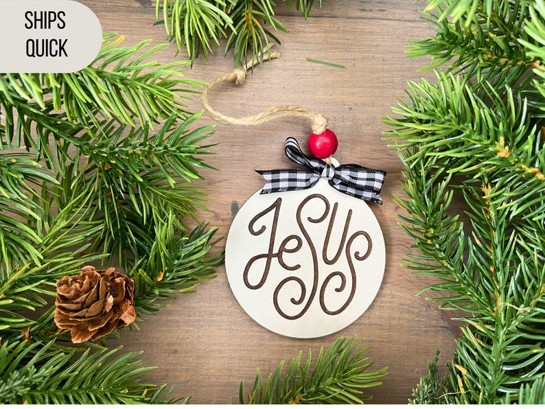 Jesus ornament with red bow and plaid ribbon and greenery.