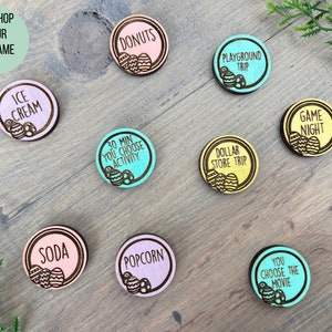 Puede incluir: Nueve fichas de huevo de Pascua de madera con diferentes actividades escritas en ellas, incluyendo "Helado", "Donas", "Viaje al parque infantil", "30 Min Usted elige la actividad", "Viaje a la tienda de un d&oacute;lar", "Noche de juegos", "Soda", "Palomitas de ma&iacute;z" y "Usted elige la pel&iacute;cula".