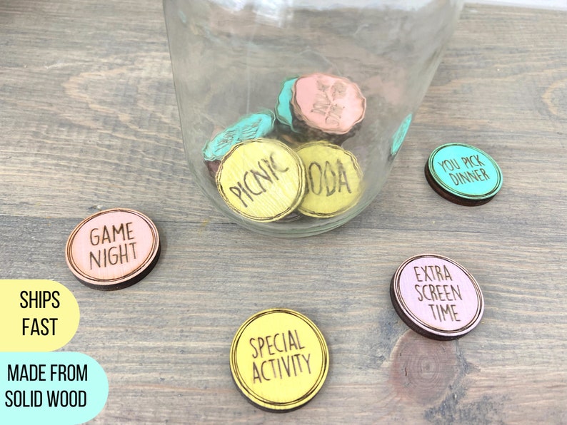 Puede incluir: Un tarro de vidrio lleno de fichas de madera de colores con frases como "Noche de juegos", "Picnic", "T&uacute; eliges la cena", "Tiempo extra de pantalla" y "Actividad especial".