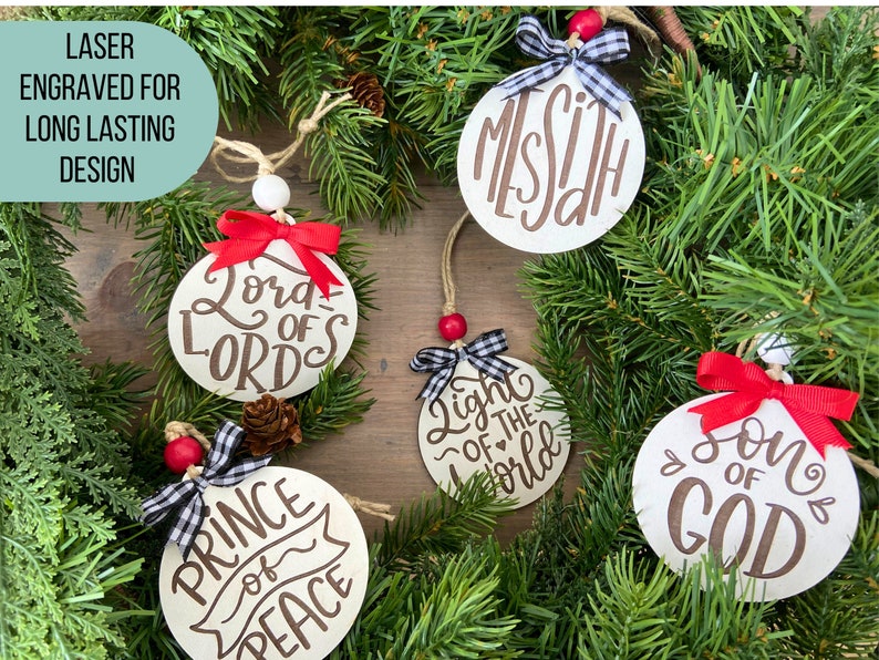 Each ornament is laser engraved. This image shows 5 ornaments. They say Messiah, Lord of Lords, Light of the world, Son of God, and Prince of Peace.