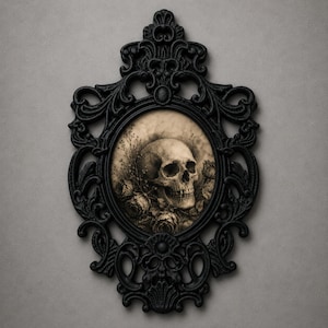 Könnte beinhalten: Ein ovaler Wandspiegel mit einem verzierten, mattschwarzen Rahmen mit komplexen Schnörkeln und Filigrandetails. Das zentrale Glas zeigt eine sepiafarbene Illustration eines menschlichen Schädels, umgeben von detaillierten Blumen.