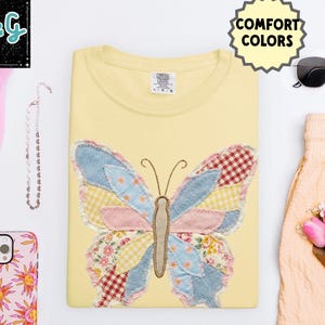 Peut inclure: Un sweat-shirt jaune clair avec un motif papillon patchwork en tissus bleus, roses et rouges. Le mot "BUTTER" est en bas &agrave; droite. Autres accessoires : lunettes de soleil, coque de t&eacute;l&eacute;phone rose et chapeau rose.