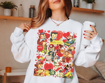 May include: White sweatshirt with a vintage Valentine's Day print featuring cartoon animals and hearts. The print includes the text "Hello Kitten", "You make a purr-fect Valentine", and "Woo, woo, be my Valentine".