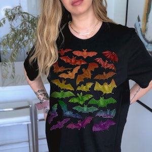 May include: A black t-shirt with a rainbow gradient of bats printed on the front. The bats are arranged in a cascading pattern, with the colors transitioning from red to purple.