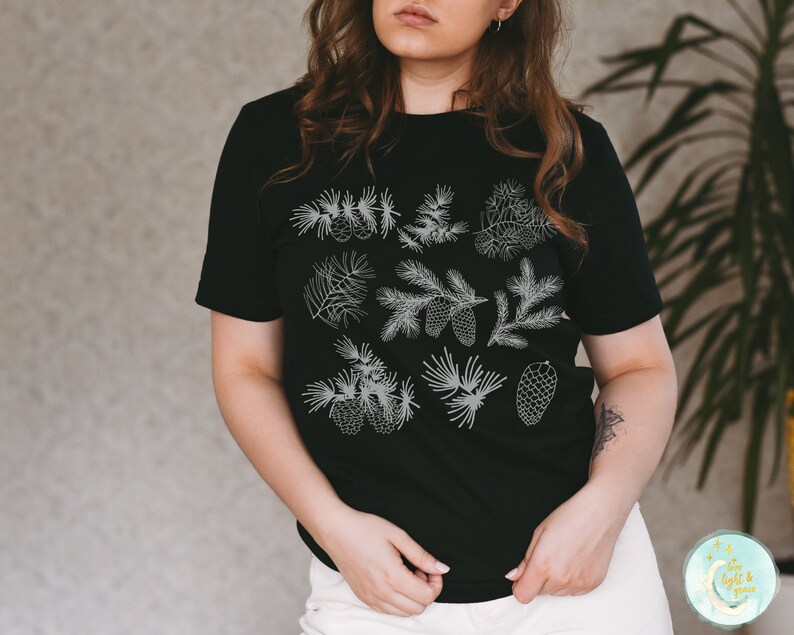 May include: A black t-shirt with a white design of pine branches and cones.