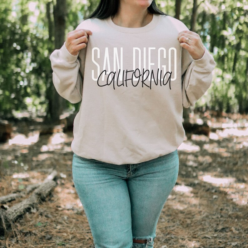 May include: A beige sweatshirt with the text "SAN DIEGO CALIFORNIA" printed in white on the front.
