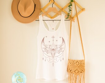 May include: White tank top with a rose gold crescent moon and lotus flower design. The text "love light & grace" is on a blue circle sticker in the bottom left corner of the image.