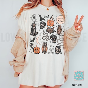 May include: A white t-shirt with a vintage Halloween design featuring black cats, owls, pumpkins, bats, skulls, snakes, and stars. The text "Boo!" and "Trick or Treat" are also included in the design.