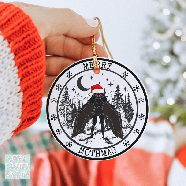 Ceramic ornament circle shaped with image of mothman with a santa hat on saying Merry Mothmas