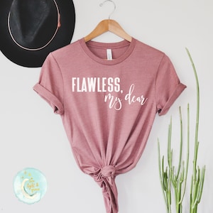 May include: A dusty rose t-shirt with the text "FLAWLESS, my dear" printed in white on the front.