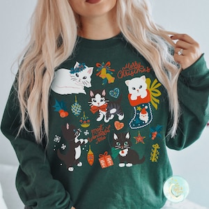 May include: Green Christmas sweater with a festive design featuring cats, ornaments, and the text "Merry Christmas" and "Most Wonderful Time".