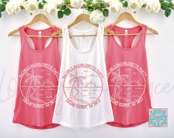May include: Three pink and white tank tops with a palm tree and sunset graphic. The text on the shirts reads "Rachel's Bachelorette Party Grand Rapids, MI 2022".
