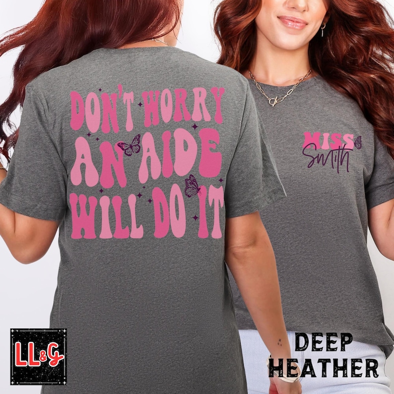 Peut inclure: Deux t-shirts gris chin&eacute; fonc&eacute;. L'un porte l'inscription rose "DON'T WORRY AN AIDE WILL DO IT" avec des papillons. L'autre affiche "Miss Smith" en rose. Les t-shirts sont &agrave; manches courtes.