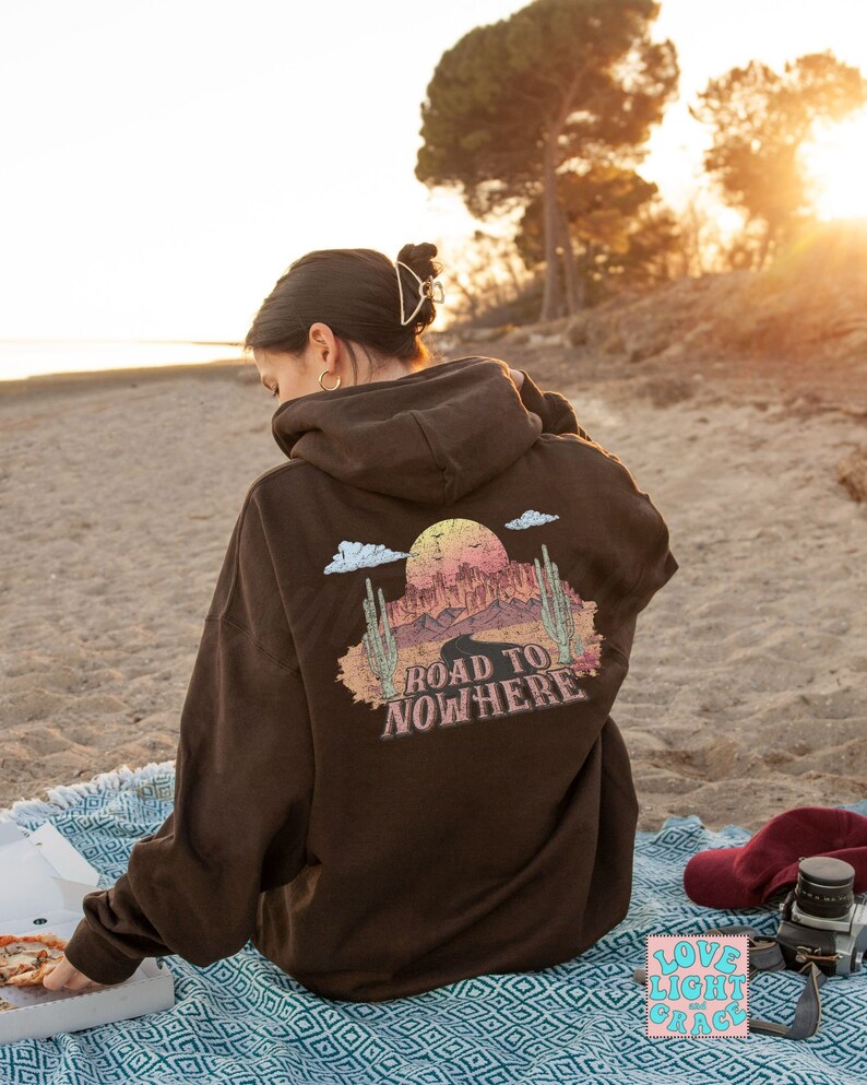 May include: Brown hooded sweatshirt with a graphic print of a desert landscape and the text "Road to Nowhere".