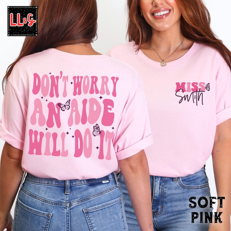 Peut inclure: T-shirt rose clair avec l'inscription "DON'T WORRY AN AIDE WILL DO IT" au dos et "MISS Smith" devant. Le motif comprend des papillons et des &eacute;toiles dans des tons de rose. Le t-shirt est &agrave; col rond.