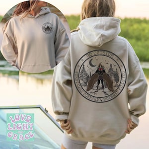 May include: A beige hoodie with a graphic on the back that says "Go Outside Worst Case Scenario, Mothman Kills You" with a drawing of a mothman in a forest scene. The hoodie has a pocket on the front and a hood.