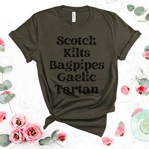 May include: A dark green t-shirt with the text "Scotch Kilts Bagpipes Gaelic Tartan" printed in black.