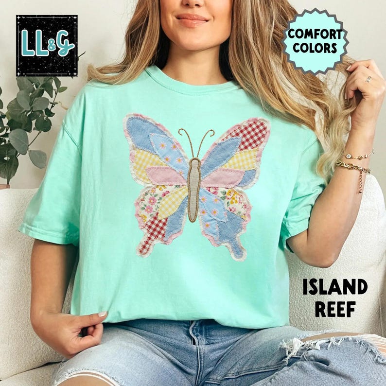 Peut inclure: T-shirt vert clair avec un grand papillon appliqu&eacute;. Le papillon a des ailes en patchwork aux motifs bleus, roses, jaunes et rouges. Le t-shirt porte les mentions "COMFORT COLORS" et "ISLAND REEF". Le logo de la marque "LL&G" est en haut &agrave; gauche.