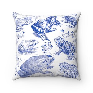May include: Square throw pillow with a white background and a blue frog illustration. The design features various frog species in a detailed, vintage style, with botanical accents.