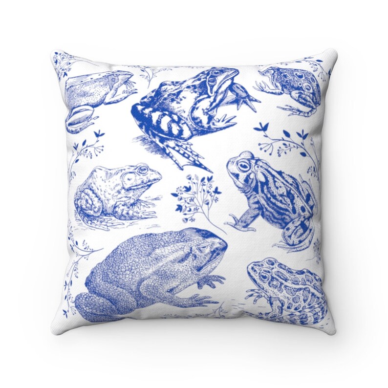 May include: Square throw pillow with a white background and a blue frog illustration. The design features various frog species in a detailed, vintage style, with botanical accents. The pillow is a decorative home accent.