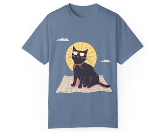 May include: A blue t-shirt featuring a black cat wearing sunglasses and a red bow tie, sitting on a checkered blanket in front of a yellow sun.