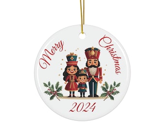 May include: White ceramic Christmas ornament with a red and gold nutcracker family, a girl, a boy, and a man, with the text "Merry Christmas 2024" in red.