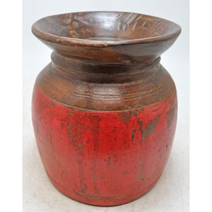 Puede incluir: Un jarrón de madera con un exterior pintado de rojo y una parte superior de madera natural. El jarrón tiene un cuerpo redondeado y una abertura ancha.