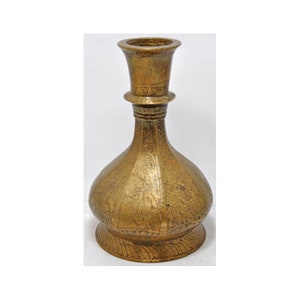 May include: A gold-colored metal vase with intricate engraved designs. The vase has a wide base and a narrow neck with a flared opening.