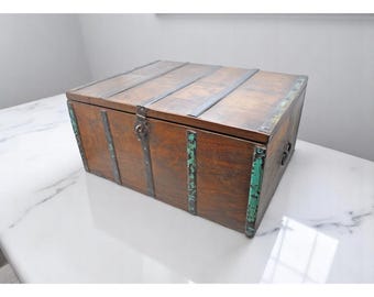 May include: A wooden chest with metal accents and a green patina. The chest has a hinged lid and a metal latch.