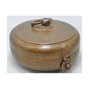 May include: A round, brass trinket box with a hinged lid and a decorative handle. The box has a worn, antique finish and intricate engraved details.