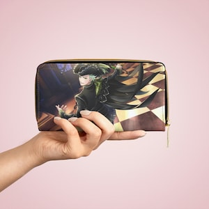 May include: A rectangular wallet with a gold zipper, featuring a colorful illustration of a character in a black outfit and hat. The background has a checkered pattern and a dark interior scene. The wallet is held by a hand.