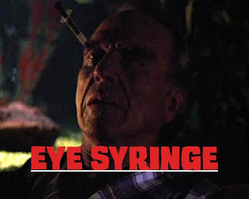 Puede incluir: Primer plano de la cara de un hombre con una jeringa insertada en su ojo. La imagen es oscura y el hombre tiene una expresi&oacute;n de dolor. El texto "EYE SYRINGE" est&aacute; superpuesto sobre la imagen.