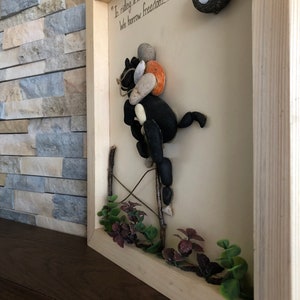 May include: A framed artwork made with stones depicting a horse and rider with the quote "In riding a horse, we borrow freedom." A horseshoe is in the upper right corner.