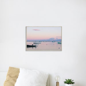 May include: A framed photograph of a seascape with a pink and purple sunset over a calm body of water. Several boats are anchored in the water, with a few small islands in the distance.