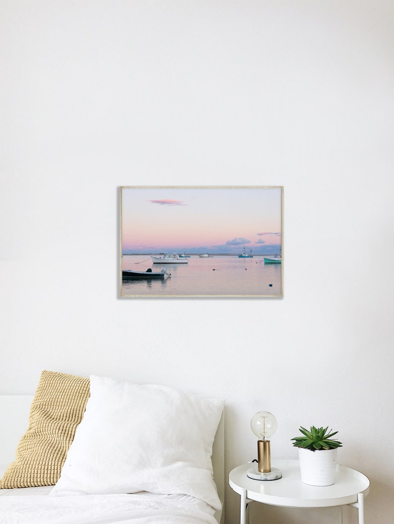 May include: A framed photograph of a seascape with a pink and purple sunset over a calm body of water. Several boats are anchored in the water, with a few small islands in the distance.