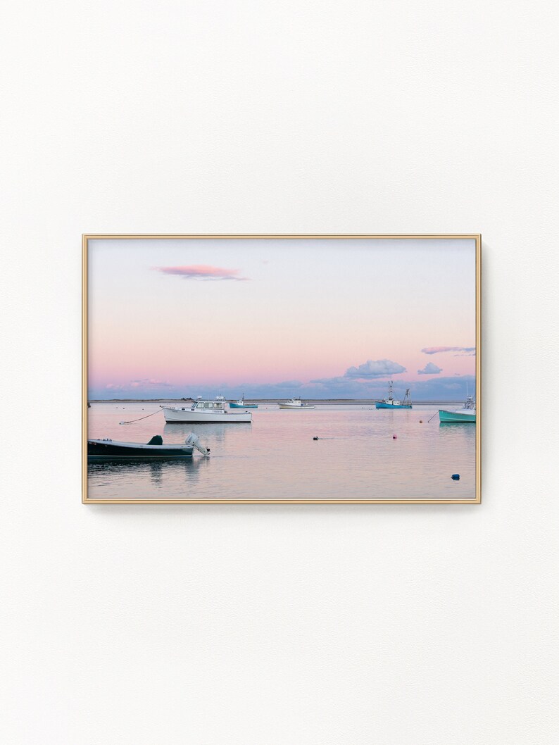 May include: A framed photograph of a seascape with a pink and purple sunset over calm water. Several boats are anchored in the water, with a few buoys visible.