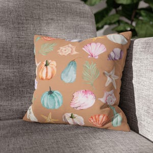 May include: A brown throw pillow with a watercolor pattern of seashells, gourds, and leaves. The pillow is decorated with a variety of colors, including pink, blue, green, and orange.
