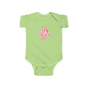 May include: A light green baby onesie with a pink diamond graphic and the text "She is more precious than gold".