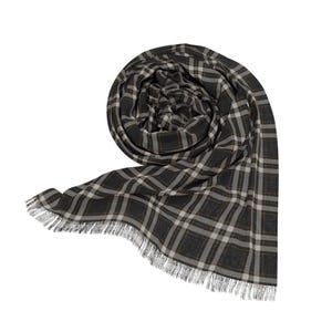 May include: A rolled-up, fringed scarf with a plaid pattern in shades of gray, white, and brown. The scarf is made of a soft material and is displayed against a white background. The fringe is at the bottom edge.