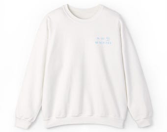 Op de afbeelding: Een witte crewneck sweatshirt met de tekst "IN MY BEACH ERA" in lichtblauw op de borst. De sweatshirt heeft lange mouwen en een relaxte pasvorm, geschikt voor casual wear.