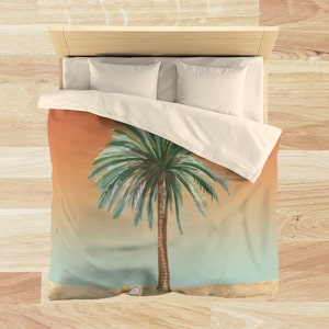 May include: A duvet cover with a watercolor illustration of a palm tree on a sandy beach with an orange to blue gradient background.