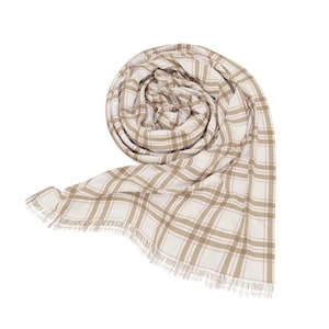 May include: A rolled-up scarf with a plaid pattern in beige, white, and light pink. The scarf has a fringed edge and is displayed against a white background. The fabric appears soft and lightweight, suitable for cooler weather.
