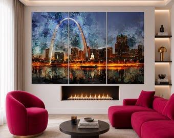 Op de afbeelding: Een driedelige wandkunstset met de St. Louis Gateway Arch en de skyline van de stad bij nacht. Het kunstwerk heeft een aquarel-esthetiek met diepblauwe, oranje en gele tinten, met de verlichte boog en de gebouwen in de stad.