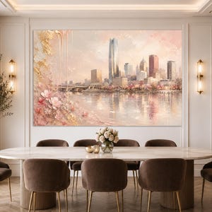 May include: A large rectangular wall art print featuring a city skyline reflected in a calm body of water. The scene is accented with textured gold leaf details and soft pink floral blossoms in the foreground, set against a pale sky.