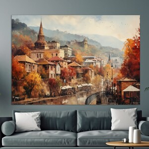 Peut inclure: Une peinture à l'aquarelle d'une ville avec une rivière qui la traverse. Les bâtiments sont un mélange d'ancien et de moderne, certains ayant des toits en tuiles rouges. Des arbres et de la végétation sont présents dans toute la scène, avec quelques oiseaux en vol au-dessus.