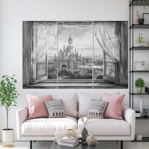 May include: Black and white canvas art set depicting a castle scene viewed through an open window with sheer curtains. The artwork is displayed above a white sofa with pink and patterned pillows. A small plant and decorative items are on a nearby table.