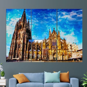 May include: A triptych canvas print of the Cologne Cathedral, showcasing its intricate Gothic architecture. The artwork features a vibrant blue sky backdrop, with the cathedral's facade rendered in shades of gold and brown.